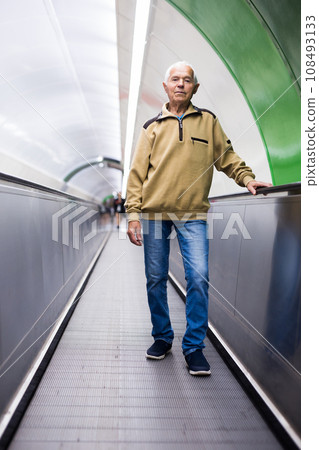 Positive mature man walking down escalator to subway station platform Positive mature man walking down escalator to subway station platform 108493133