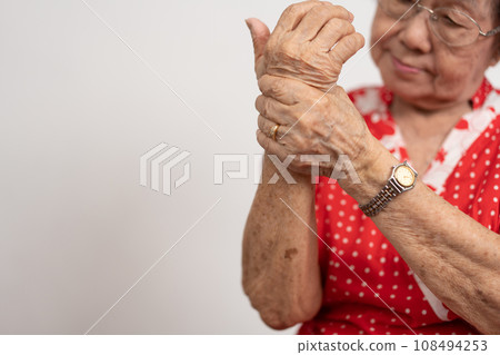 Elderly Asian woman patients suffer from numbing pain in hands from rheumatoid arthritis. Senior woman massage her hand with wrist pain. Concept of joint pain, rheumatoid arthritis, and hand problems. 108494253