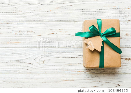 wrapped christmas or other holiday handmade present in paper with colored ribbon. Present box, decoration of gift on colourfull table, top view with copy space 108494555