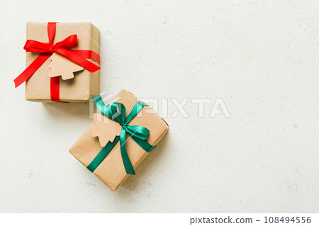 wrapped christmas or other holiday handmade present in paper with colored ribbon. Present box, decoration of gift on colourfull table, top view with copy space wrapped christmas or other holiday handmade present in paper with colored ribbon. Present box, decoration of gift on colourfull table, top view with copy space 108494556