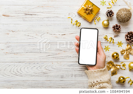 christmas mockup with space for text. christmas advertising, app template. hand holding phone with empty screen on table background. Happy New Year and Xmas Flat lay christmas mockup with space for text. christmas advertising, app template. hand holding phone with empty screen on table background. Happy New Year and Xmas Flat lay 108494594