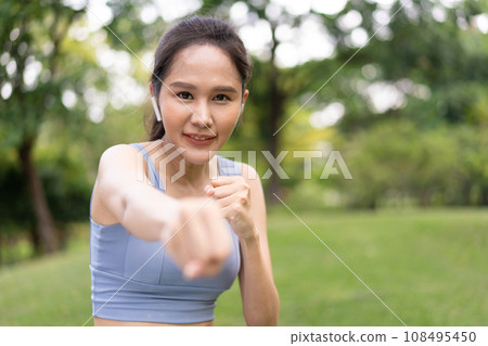 Fitness Asian Girl in tight sportswear doing exercises and punching boxing footwork cardio exercise in park. Female student boxer motivation. 108495450