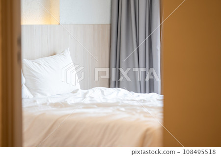Close up single beds with white bedding are in the cream bedroom of hotel that turn on the headboard light and open the gray curtain. 108495518
