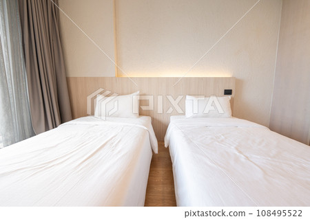 2 single beds with white bedding are in the cream bedroom of hotel that turn on the headboard light and open the gray curtain. 2 single beds with white bedding are in the cream bedroom of hotel that turn on the headboard light and open the gray curtain. 108495522