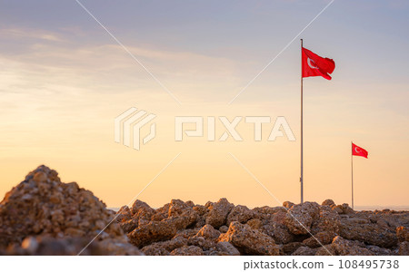 travel to ancient city of Side, Antalya coast of Turkey in tourist low season. Turkish flags on famous embankment in Side against background of sunset sky travel to ancient city of Side, Antalya coast of Turkey in tourist low season. Turkish flags on famous embankment in Side against background of sunset sky 108495738