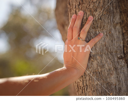 female hand gently touches bark of old olive tree. embracing fresh air and engaging in outdoor activities. Friluftsliv concept means spending as much time outdoors as possible 108495860