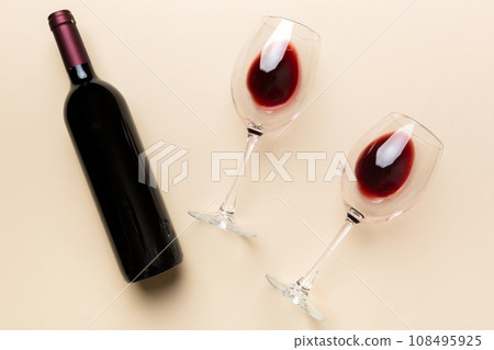 Glass of red wine and a bottle on colored table. Flat lay, top view wth copy space Glass of red wine and a bottle on colored table. Flat lay, top view wth copy space 108495925