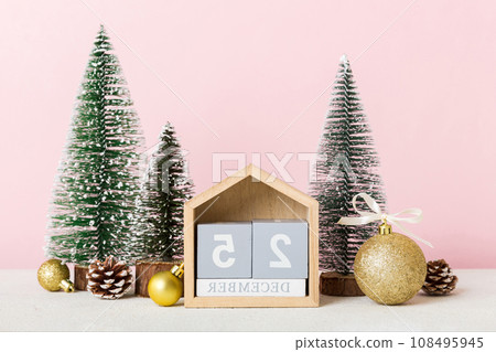 25 december. Christmas composition on colored background with a wooden calendar, with a gift box, toys, bauble copy space 25 december. Christmas composition on colored background with a wooden calendar, with a gift box, toys, bauble copy space 108495945