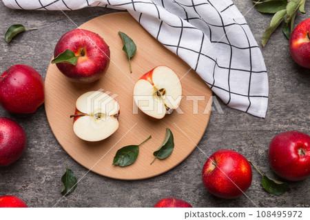 Fresh red apples with green leaves on table. cutting board with knife. Top view Fresh red apples with green leaves on table. cutting board with knife. Top view 108495972