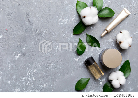 Organic cosmetic products with cotton flower and green leaves on cement background. Copy space, flat lay 108495993