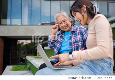 Focused young students listening old senior aged teachers for advise capstone project in university. Happy middle aged teacher working together with students for graduation project. 108496536