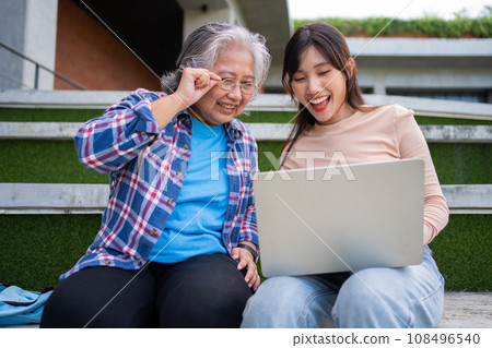 Focused young students listening old senior aged teachers for advise capstone project in university. Happy middle aged teacher working together with students for graduation project. 108496540