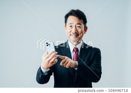 一位老人正在操作智慧型手機。 （灰色背景） 108496718