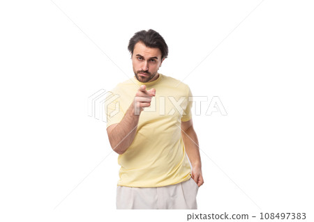 caucasian smart brutal charming guy with a beard dressed in a summer t-shirt points his finger at caucasian smart brutal charming guy with a beard dressed in a summer t-shirt points his finger at 108497383