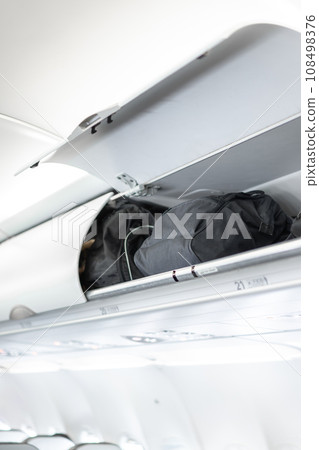 luggage on the top airplane shelf overhead passenger seat luggage on the top airplane shelf overhead passenger seat 108498376