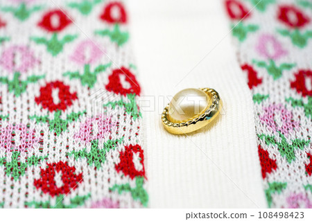 Close up to knitting flower pink and red sweater pearl gold circle buttons on the top of tshirt sweater. Close up to knitting flower pink and red sweater pearl gold circle buttons on the top of tshirt sweater. 108498423