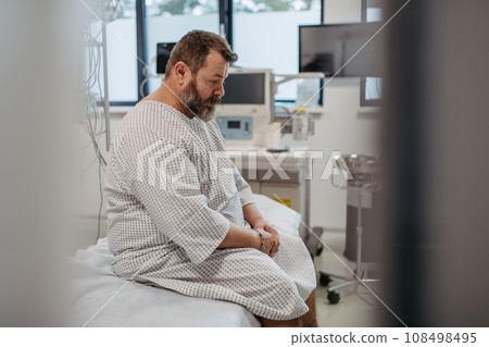 Overweight patient in hospital gown waiting for medical examination, test results in hospital, feeling anxious. Patient feeling dizzy, have vertigo and intense pain. 108498495
