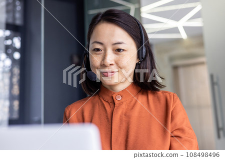 Serious Asian woman listening online conversation close up, businesswoman with headset phone, online customer support worker, working with laptop, video call consultation. 108498496