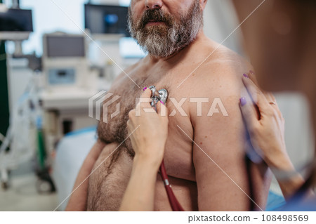 Female doctor listening to heartbeats and rhytm of overweight patient using stethoscope, detecting murmurs, irregularities, heart palpitations. Obesity affecting middle-aged men's health. Concept of 108498569