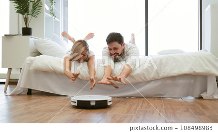 Family husband and wife on bed playing with cleaning robot Family husband and wife on bed playing with cleaning robot 108498983