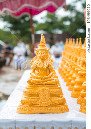 Golden Buddha statues placed on the white table, which were wet by rain felled and prepared for a religion ceremony event. 108499010