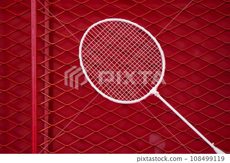 one badminton racket is hung on red grill by a cable tie for display in exhibition sports event 108499119