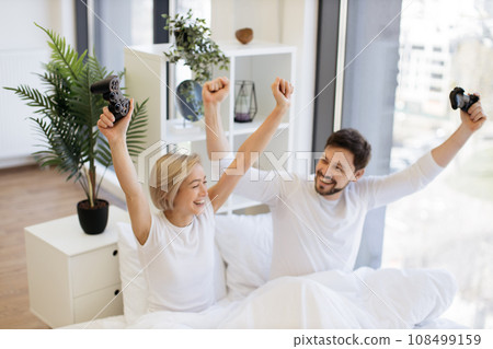 Caucasian couple in love looking at tv have fun competing in video game Caucasian couple in love looking at tv have fun competing in video game 108499159