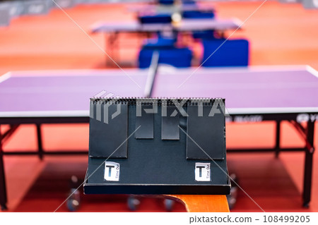 A tennis table black scoreboard is placed next to the table tennis table for referee count the score, which acts as a blurred background of pingpong tournament. 108499205