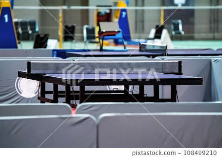 Blue table tennis or pingpong table is settle on a red, orange floor of the indoor court stadium for competitions tournament. 108499210