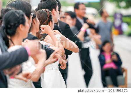 Various brides and grooms are warming up at starting line in preparation for race in order to win and receive payment for their ideal wedding. Various brides and grooms are warming up at starting line in preparation for race in order to win and receive payment for their ideal wedding. 108499271