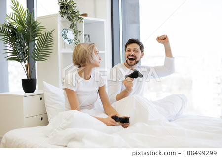 Caucasian couple in love have fun competing in laptop game using joysticks 108499299