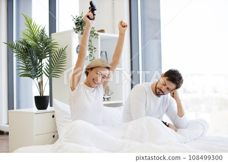 Caucasian couple in love have fun competing in laptop game using joysticks Caucasian couple in love have fun competing in laptop game using joysticks 108499300