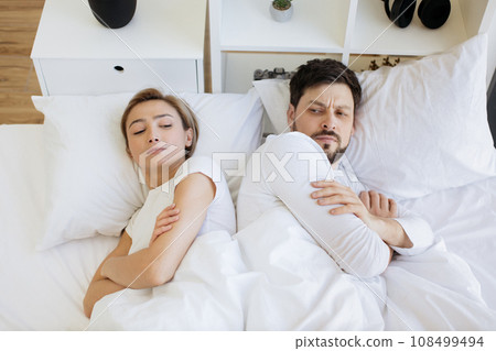 Offended caucasian woman lying on white pillow covered with a blanket. Offended caucasian woman lying on white pillow covered with a blanket. 108499494