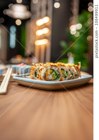 Sushi roll with tuna flakes, tempura shrimp, mango and cucumber on a plate Sushi roll with tuna flakes, tempura shrimp, mango and cucumber on a plate 108499911