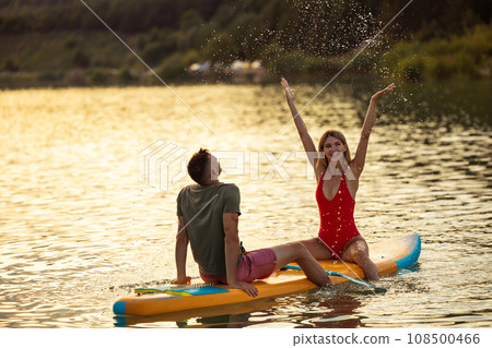 Surfers man and woman on sunset resting on the water. 108500466