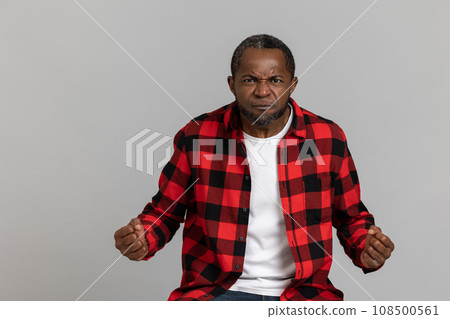 Angry black bearded man wearing red checkered shirt expressing aggression 108500561