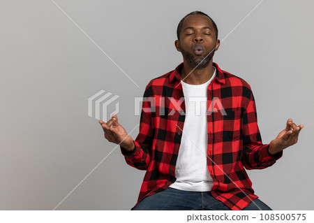 Relaxed black bearded man wearing red checkered shirt practicing yoga Relaxed black bearded man wearing red checkered shirt practicing yoga 108500575