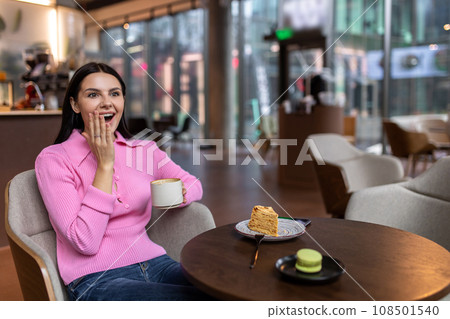 A girl in a pink shirt sitting in a cafe and feeling positive 108501540
