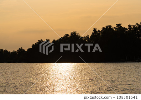 Scenery of the riverside at Chachoengsao as the sunset. We could see the partially cloudy sky and the light falling on the river was quite orange. 108501541