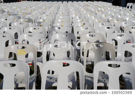 Many white plastic chairs were set up in a square area with the row and column for outdoor concerts or open air events. 108501569
