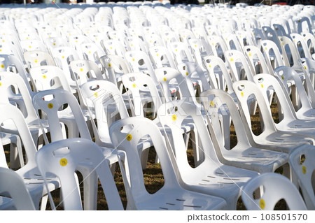 Many white plastic chairs were set up in a square area with the row and column for outdoor concerts or open air events. Many white plastic chairs were set up in a square area with the row and column for outdoor concerts or open air events. 108501570