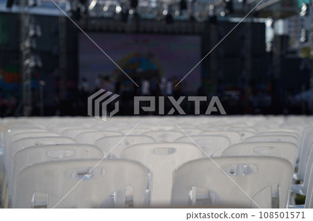 Many white plastic chairs were set up in a square area with the row and column for outdoor concerts or open air events. Many white plastic chairs were set up in a square area with the row and column for outdoor concerts or open air events. 108501571