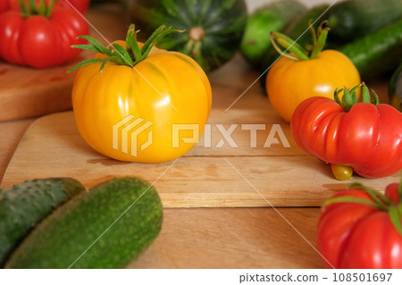 Fresh ripe big tomatoes, eggplant, veggies on a kitchen wooden workplace. Many raw vegetables background. Tomato, cucumbers. Cooker at home making a healthy veggie meal. Preparing vegetarian dish 108501697