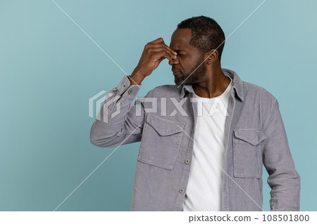 Unhappy black man wearing gray shirt grimacing Unhappy black man wearing gray shirt grimacing 108501800