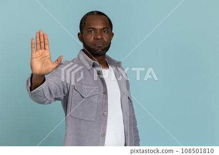 Serious black man wearing gray shirt showing stop sign 108501810