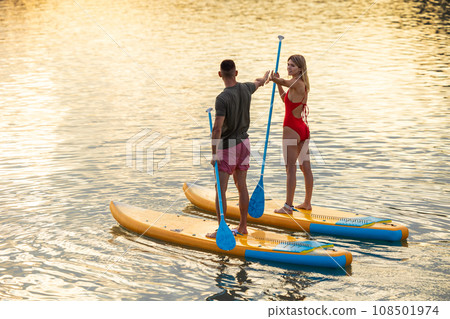 Man and woman with athletic body on surf board on river. Man and woman with athletic body on surf board on river. 108501974