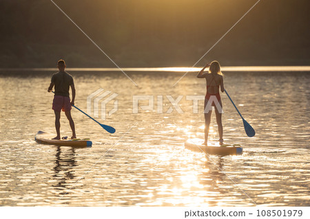 Man and woman sup board surfers at sunset. Man and woman sup board surfers at sunset. 108501979