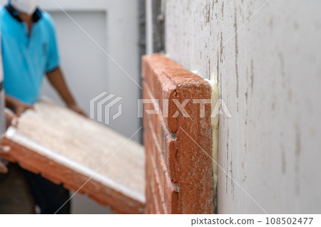Closeup to the foam brick installation by foam glue stick on cement wall at outdoor field Closeup to the foam brick installation by foam glue stick on cement wall at outdoor field 108502477