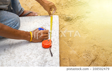 Worker is measure brick foam plate board before installation on construction site by tapeline. Worker is measure brick foam plate board before installation on construction site by tapeline. 108502479