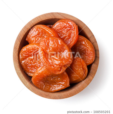 Dried apricots in a wooden plate on a white background. Top view 108503201